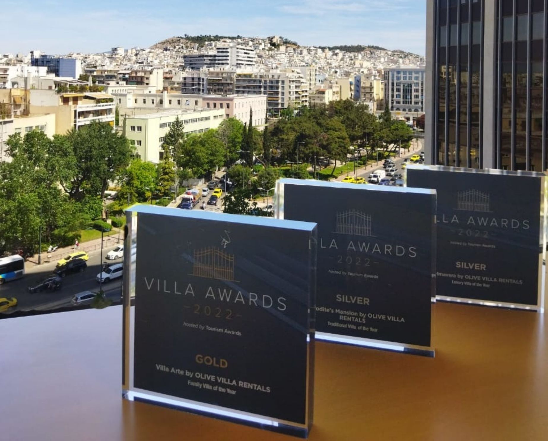 three awards lined up at Olive Villa Rentals office with the view of Athens
